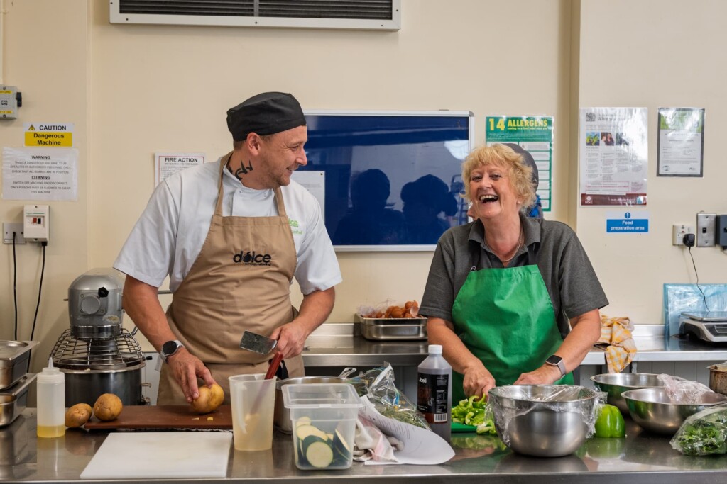 Two people laughing while working in the kitchen